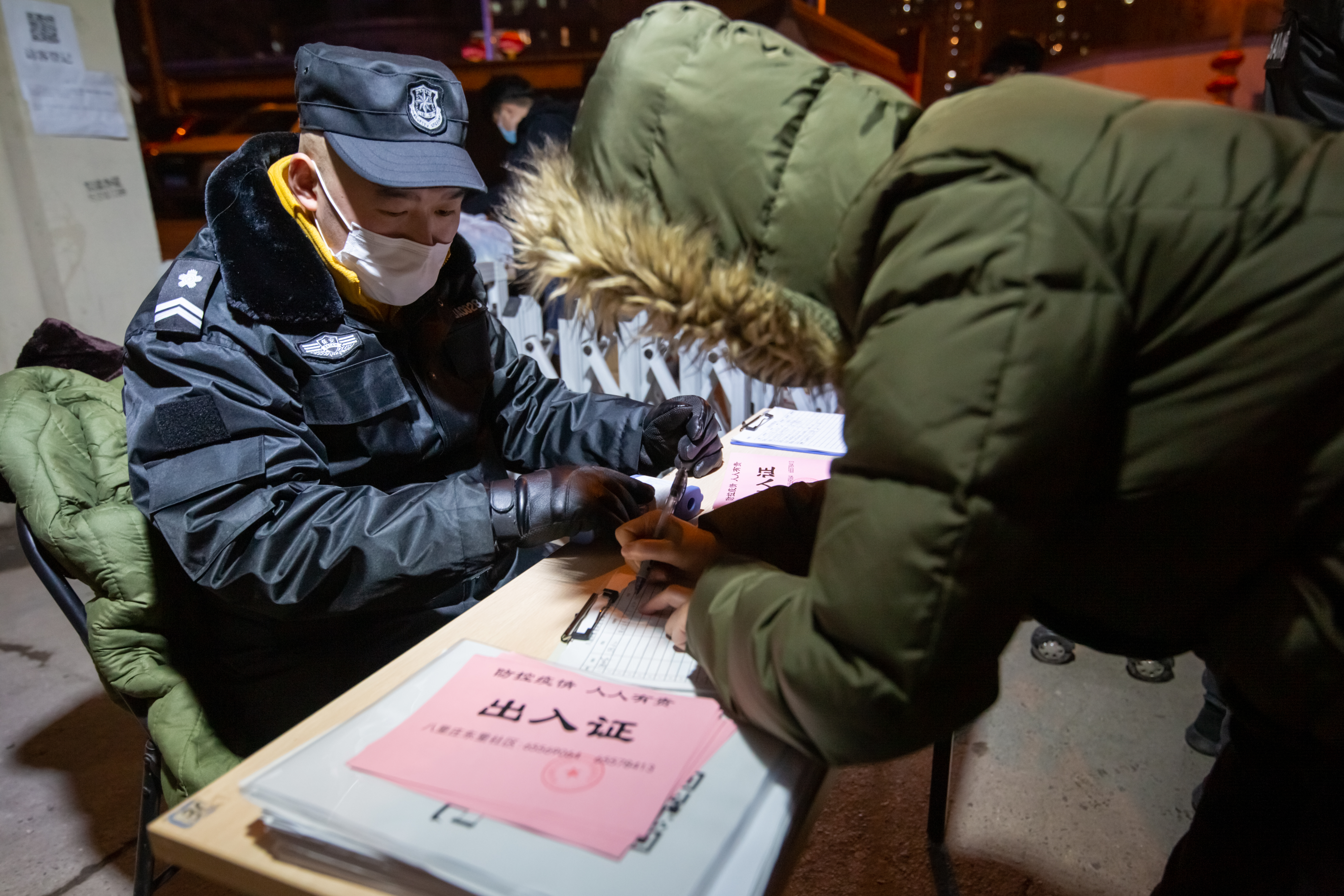 BEIJING, CHINA, FEBRUARY 10, 2020: A security guard operates a checkpoint to record citizens movement, helping control the spread of the COVID-19 virus. By Graeme Nicol, Shutterstock