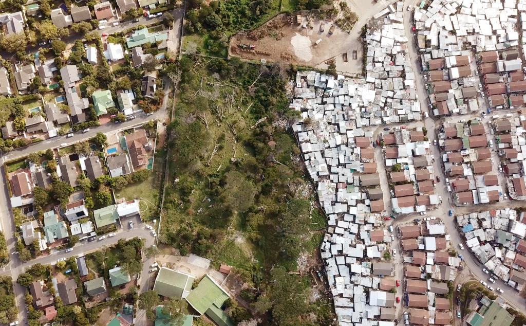 Rich houses and poor houses divided by a fence