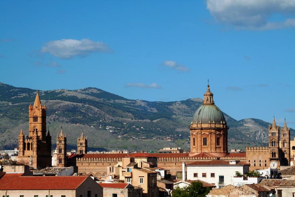 Sunlit buildings in Palermo are set against a mountainous backdrop