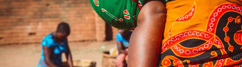 African woman carrying her baby on the market