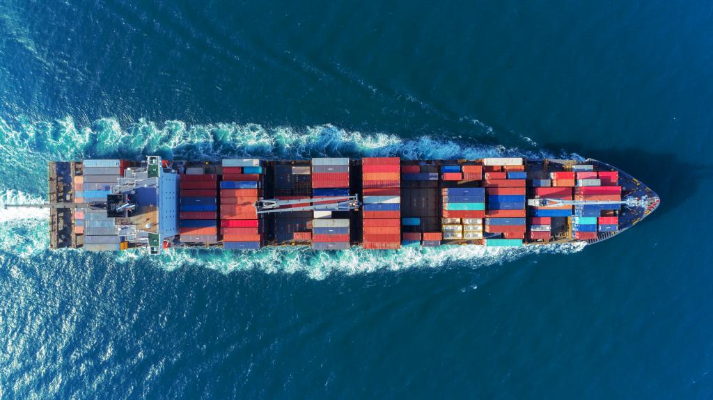 A boat full of colorful shipping containers crosses a body of water. 
