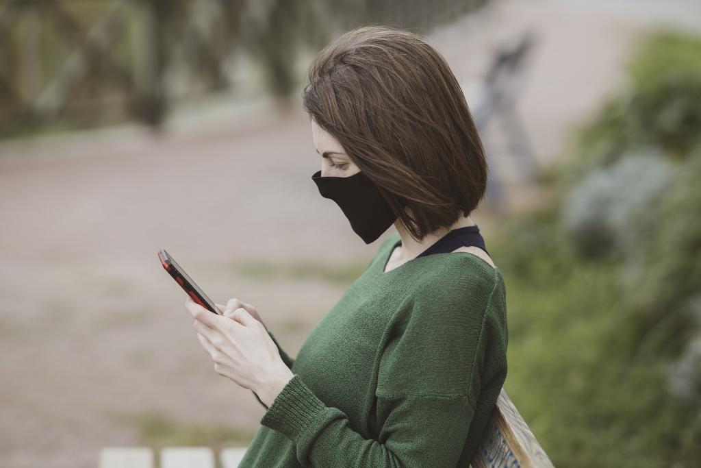 Person with face mask holding a phone