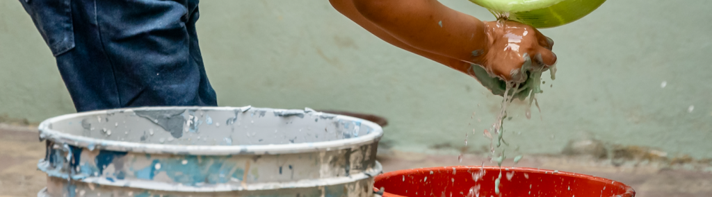 Young child washing hands with bucket