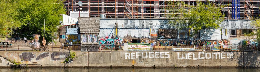YAAM night club with sign “Refugees Welcome!” along the Spree riverbank in Berlin.