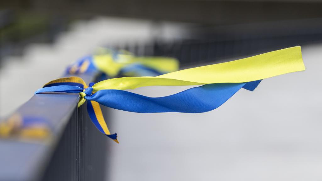 Blue and yellow ribbons are tied to a barricade to show solidarity with Ukraine. 