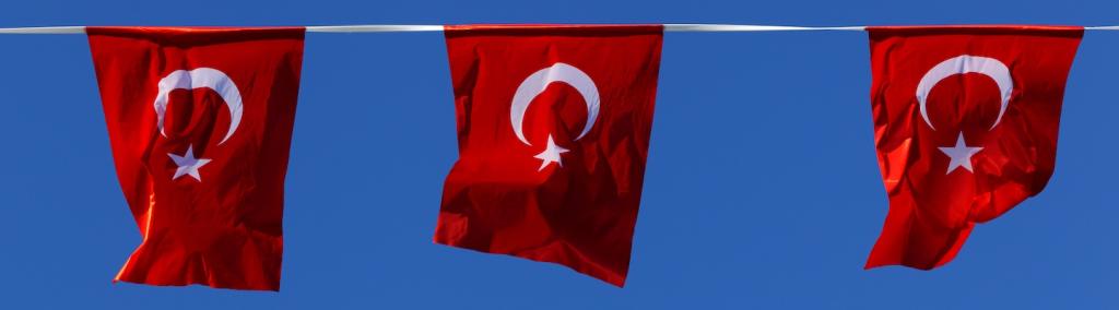 Three red Turkish flags with sunny blue-sky background