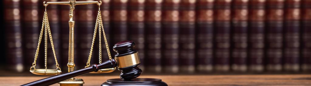 Wooden gavel and golden scale on a table.