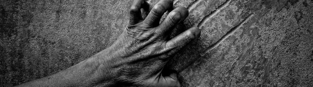 Black and white image of a hand scratching a wall, illustrating despair, hopelessness, pain, violence.