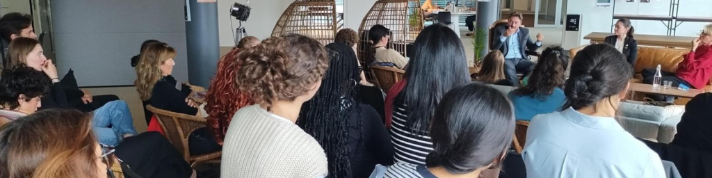Audience seated indoors listening to a speaker in a casual discussion setting