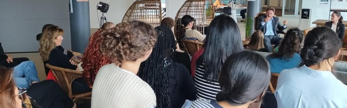 Audience seated indoors listening to a speaker in a casual discussion setting