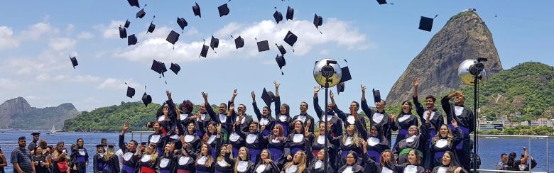 Brazilian students throw their caps in the air after graduating