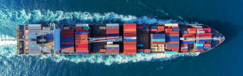 A boat full of colorful shipping containers crosses a body of water. 