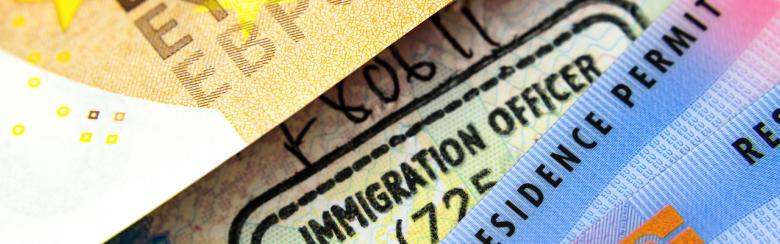UK biometric residence permit cards, immigration stamp in passport and part of a euro banknote.
