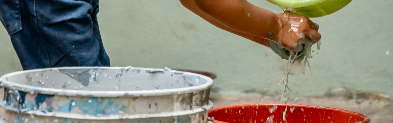 Young child washing hands with bucket
