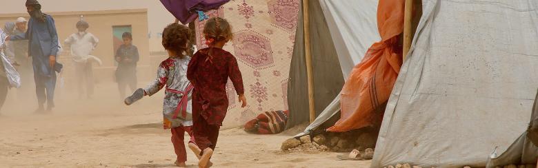 Des enfants courent pour se mettre à l’abri des tourbillons de poussière soulevés par les rafales de vent au camp de déplacés internes de Nawabad Farabi-ha.