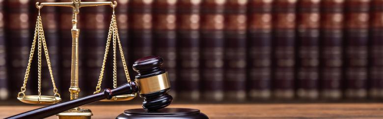 Wooden gavel and golden scale on a table.