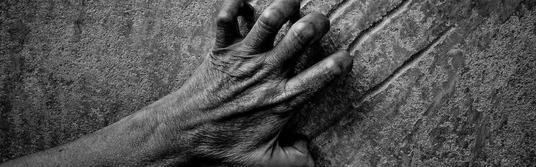 Black and white image of a hand scratching a wall, illustrating despair, hopelessness, pain, violence.