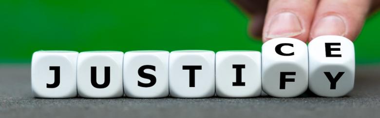 Hand turns dice and changes the word “justify” to “justice”.