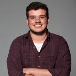 Photo of Leandro wearing a brown shirt on a grey background.