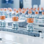The image shows a vaccine vial production line.